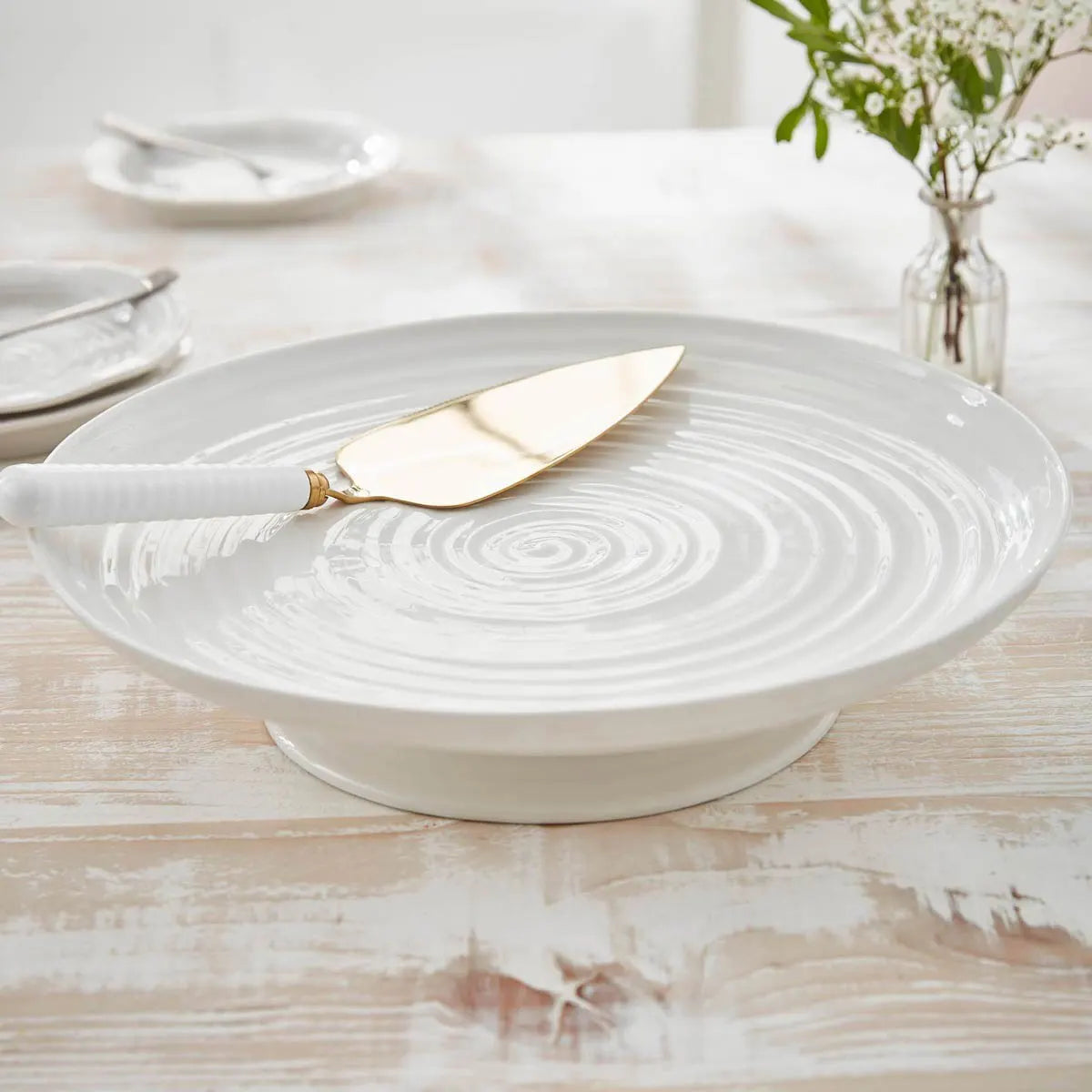 White ceramic platter with gold knife on a wooden table