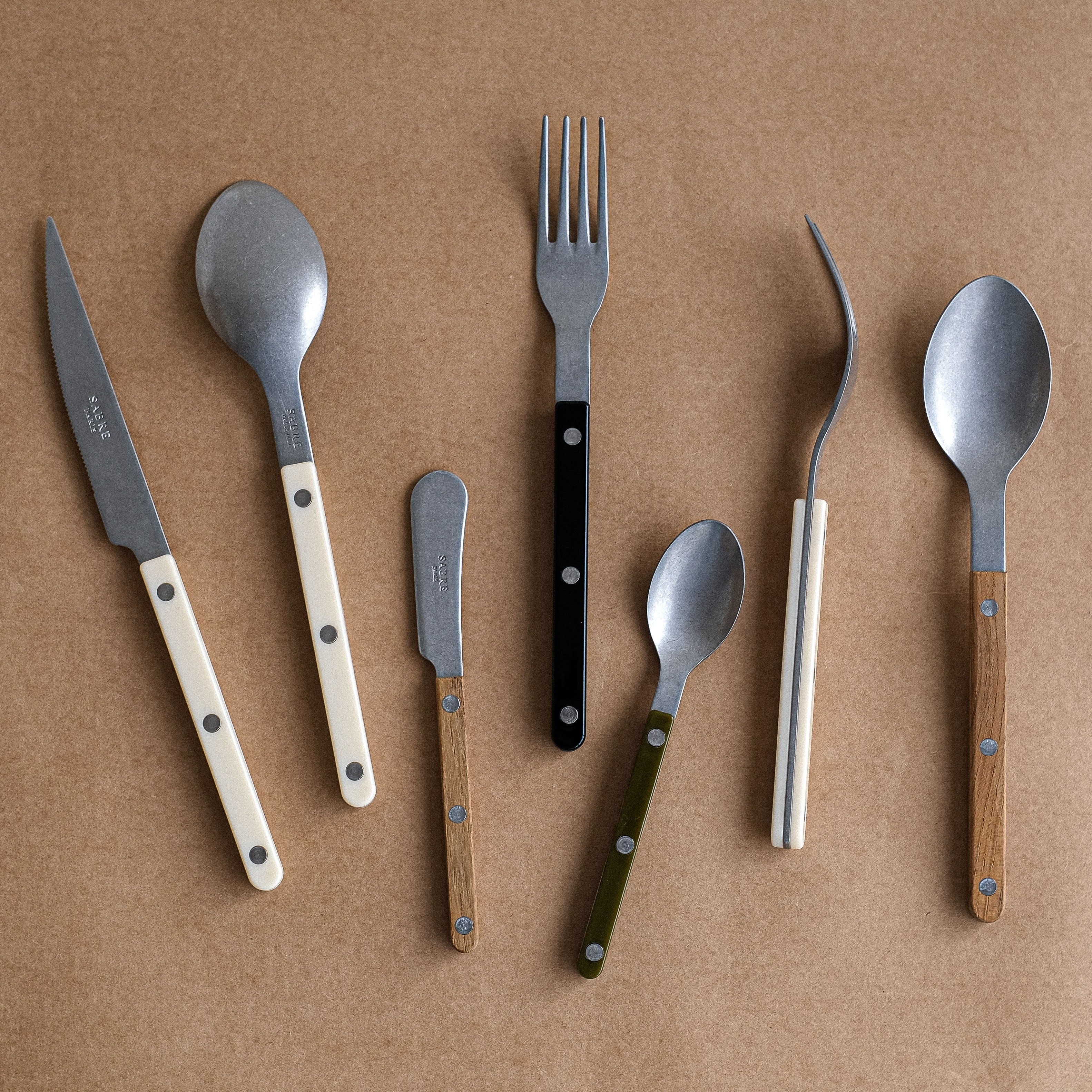 Set of cutlery including knives, spoons, and forks on a brown background