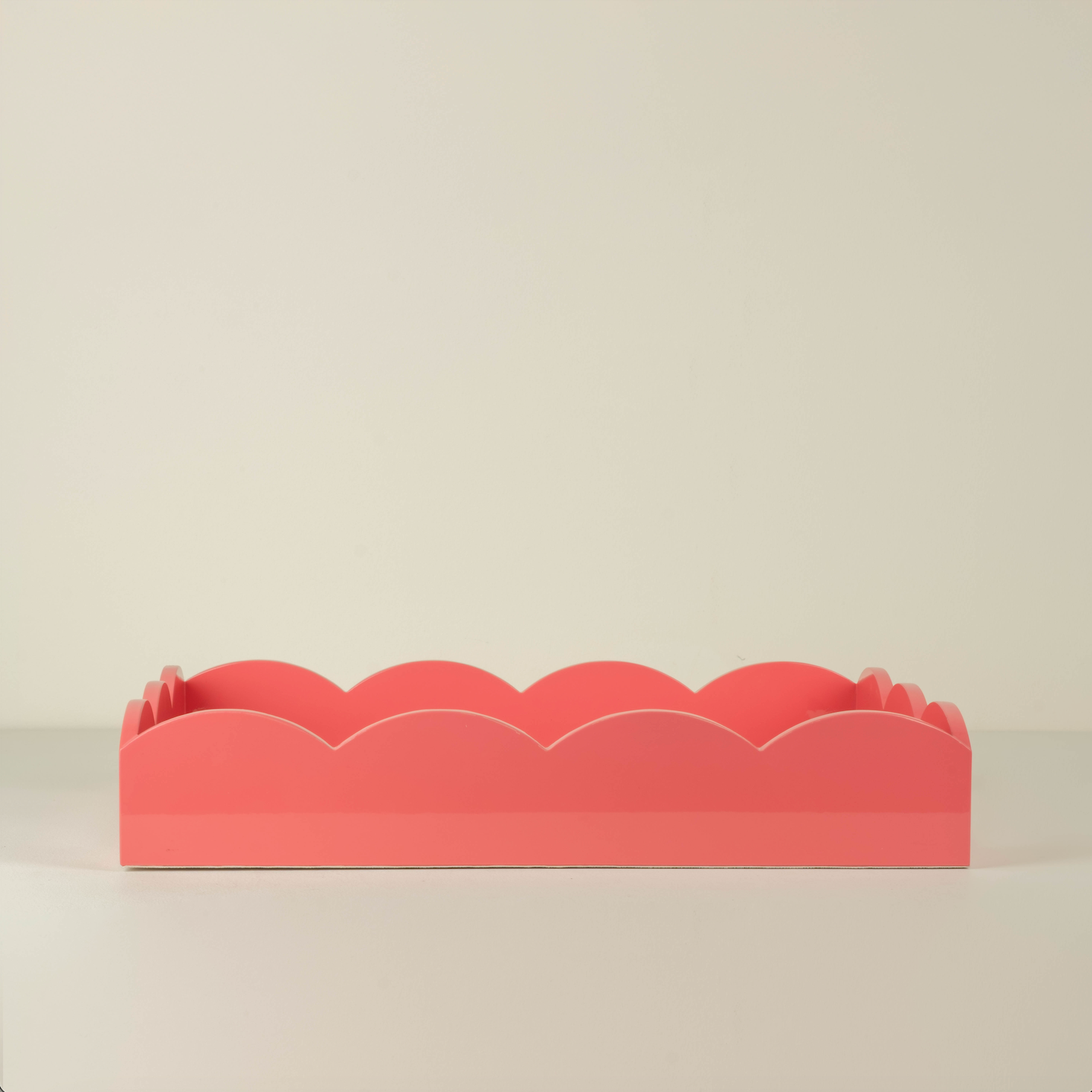 Coral-colored decorative item with scalloped edges on a beige background