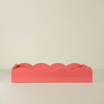 Coral-colored decorative item with scalloped edges on a beige background