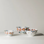 Set of four ceramic bowls with floral patterns on a light gray background