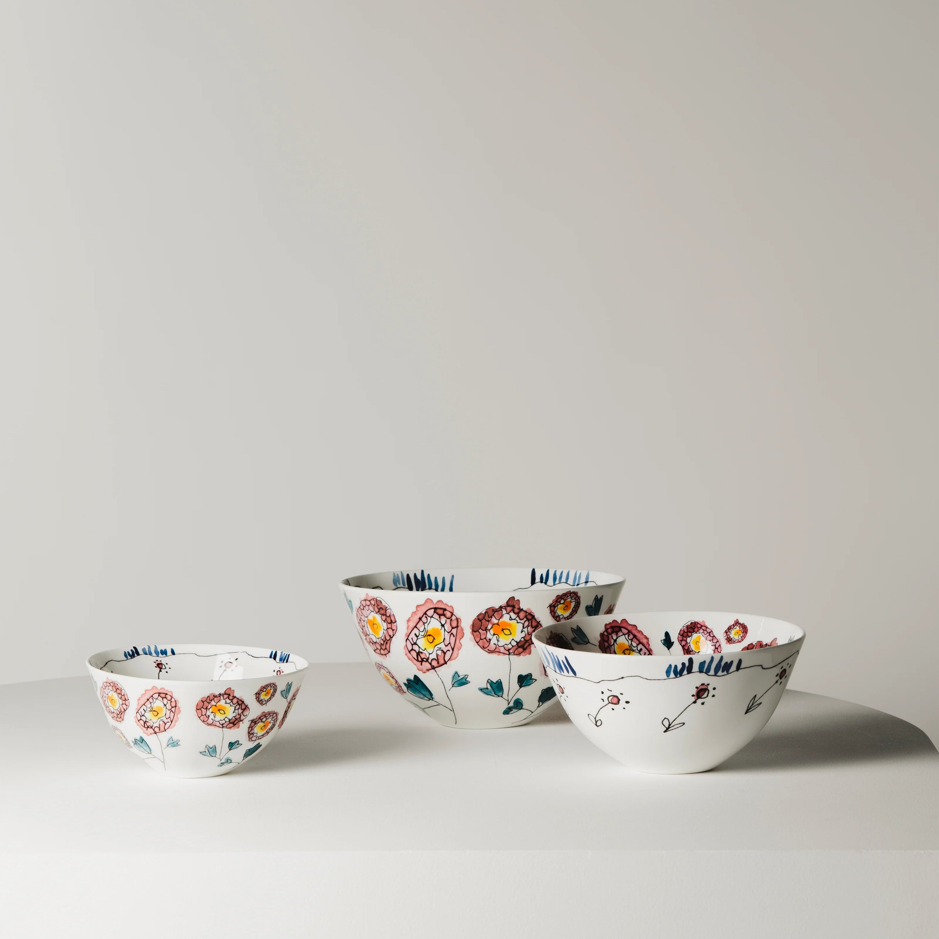 Set of four ceramic bowls with floral patterns on a light gray background