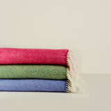 Stack of colorful woven blankets on a neutral background