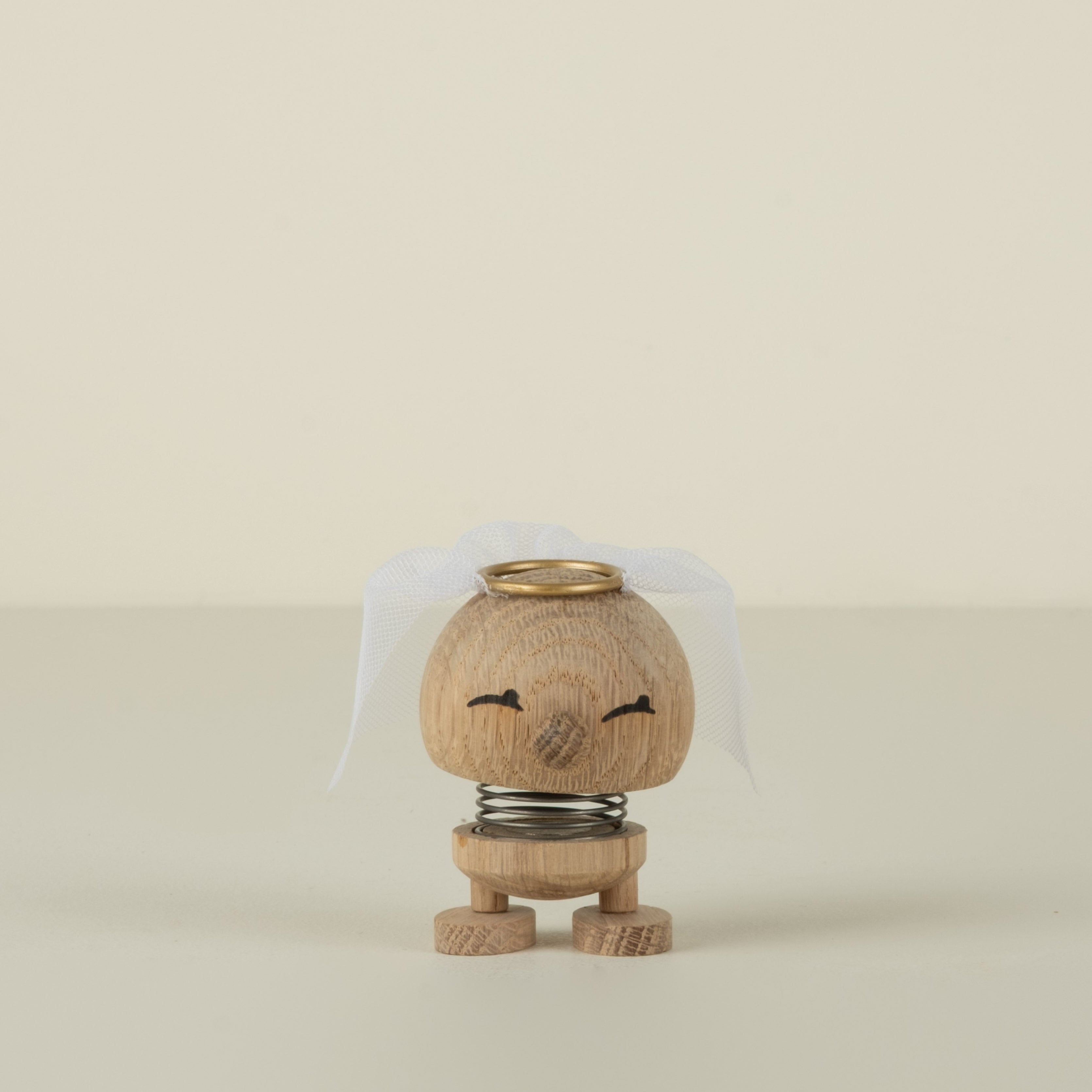Small bride wooden figurine with a gold top on a beige background