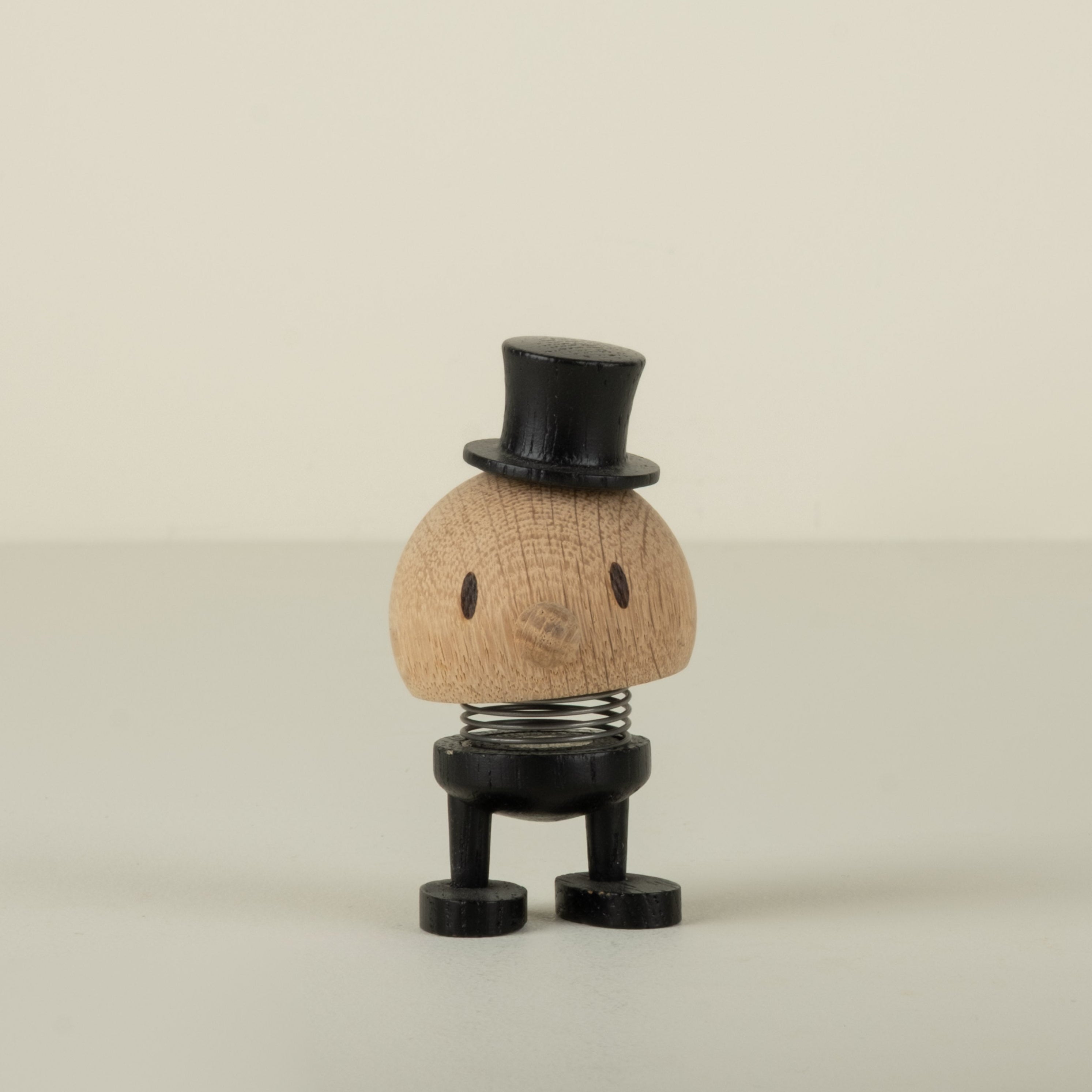 Small decorative wood groom figure with a top hat on a beige background