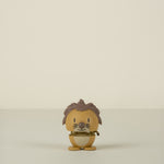 Small figurine of a lion character with brown hair and a yellow outfit on a beige background