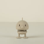 Small beige figure on a plain background