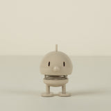 Small beige figure on a plain background
