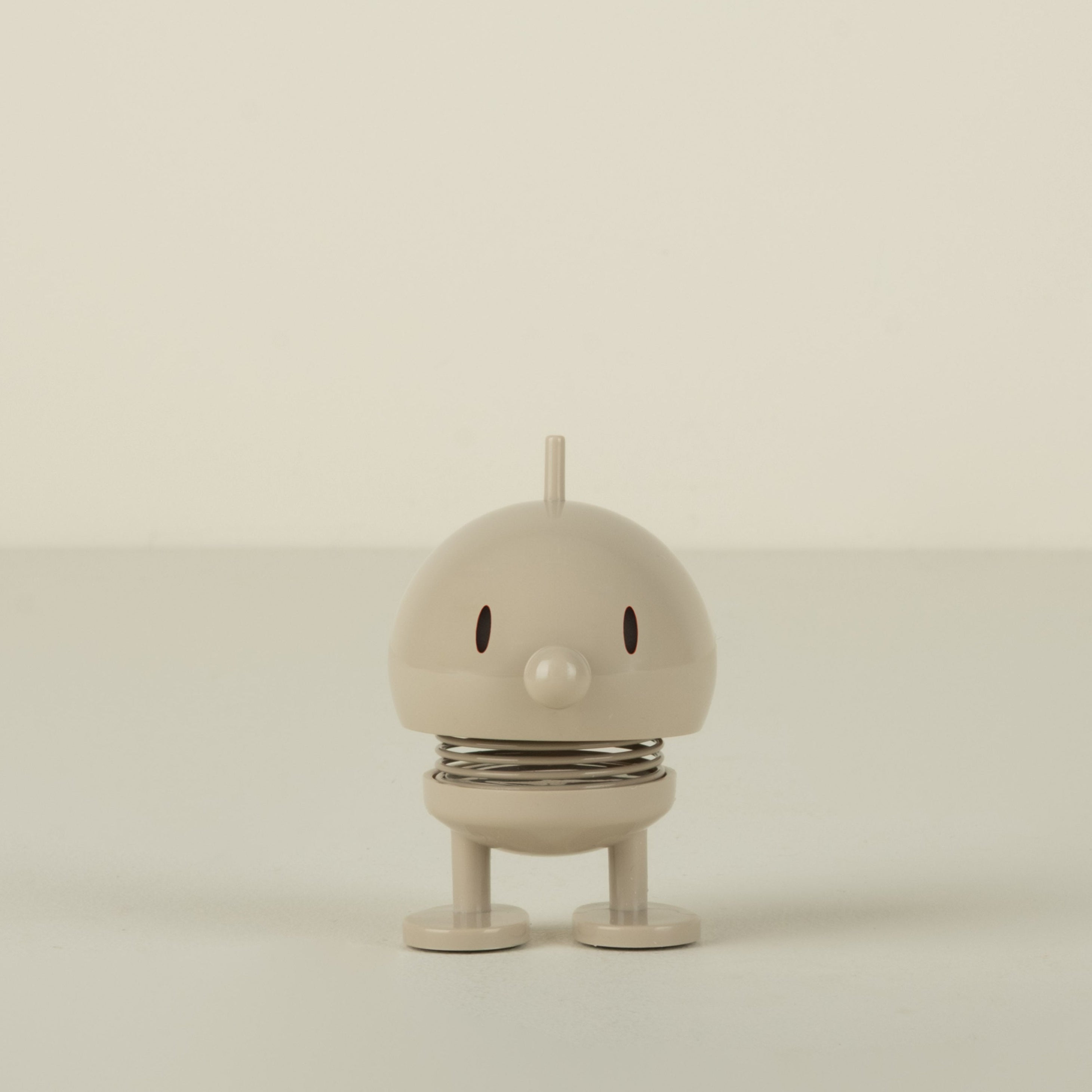 Small beige figure on a plain background