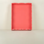 Rectangular pink tray with scalloped edge on a beige background