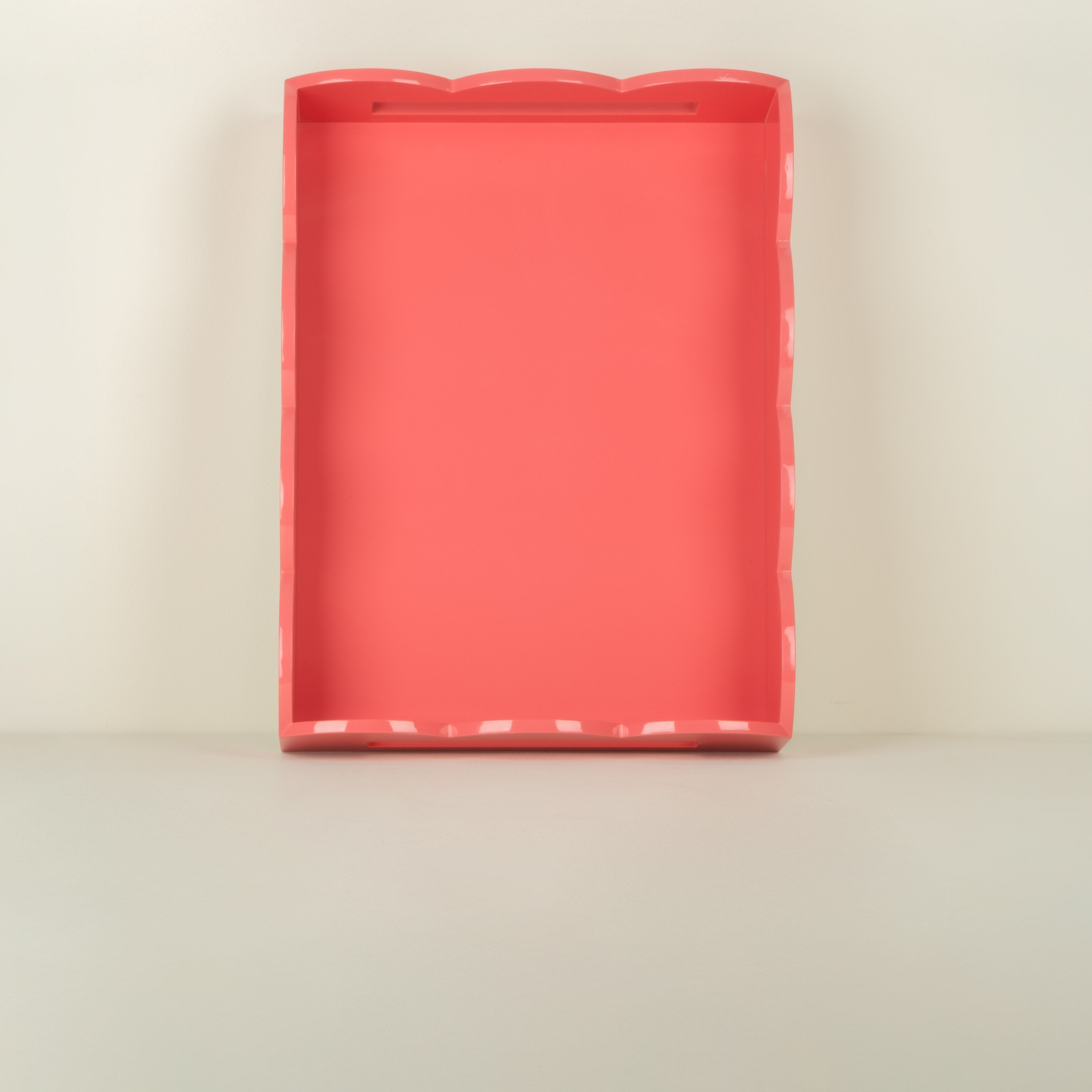 Rectangular pink tray with scalloped edge on a beige background