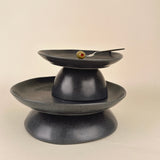 Black ceramic three-tiered stand on a beige background