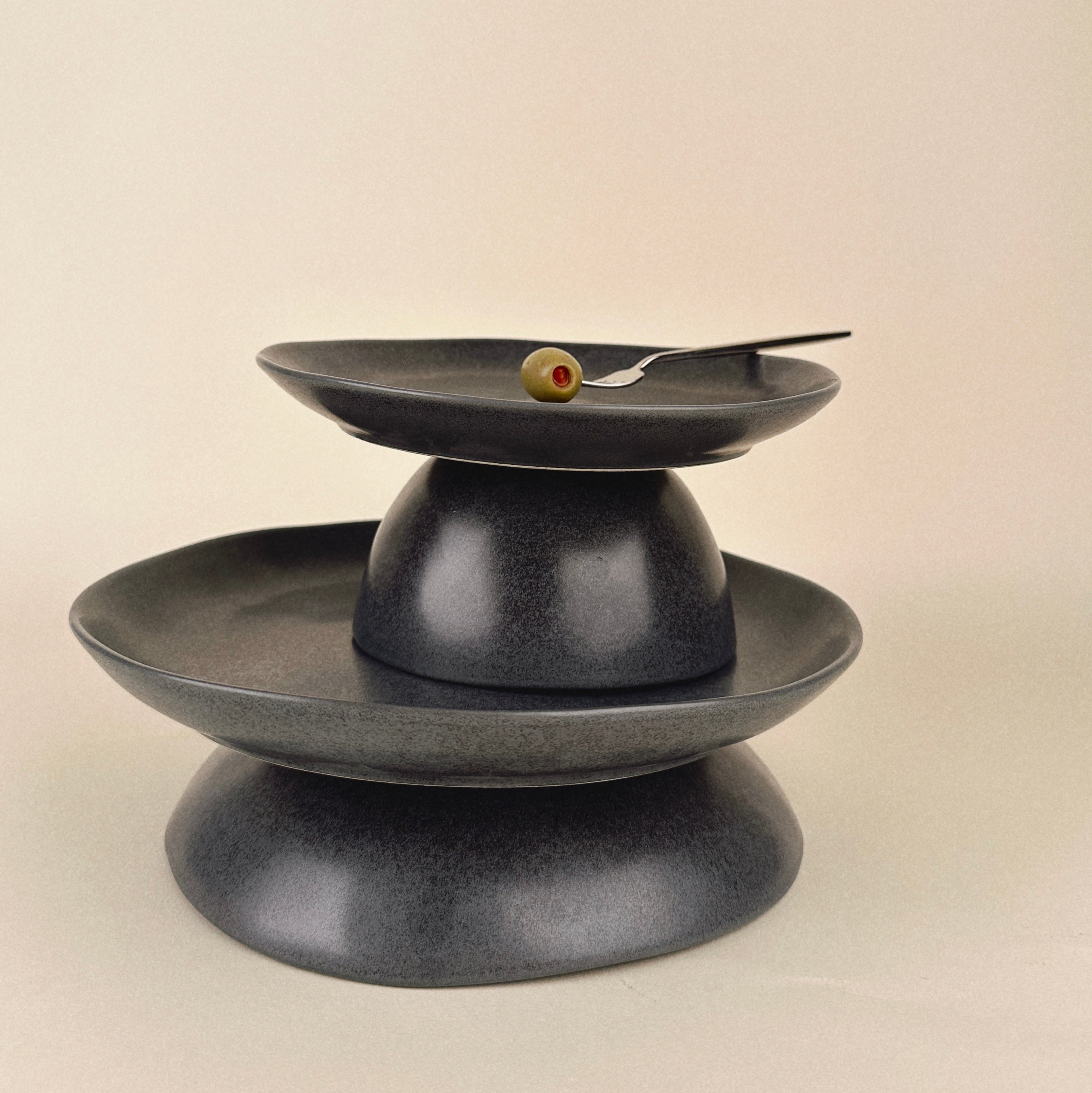 Black ceramic three-tiered stand on a beige background
