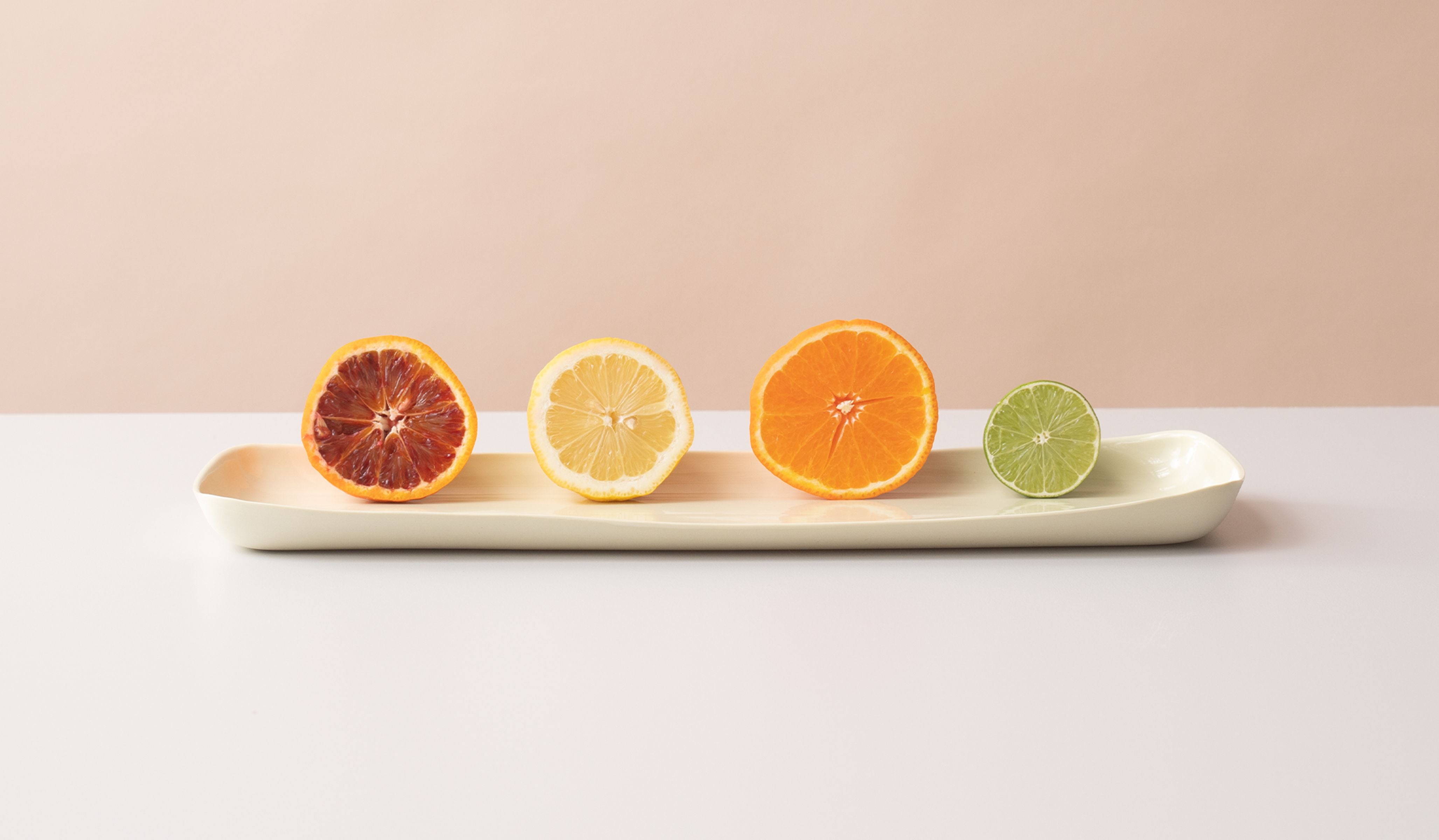 Sliced citrus fruits on a white tray with a neutral background