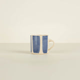 Mug with blue interior and beige exterior on a light beige background