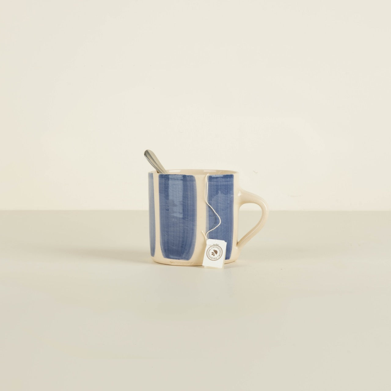 Mug with denim sleeve and spoon on a beige background
