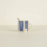 Mug with denim sleeve and spoon on a beige background
