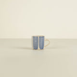 Ceramic mug with blue and white pattern on a beige background