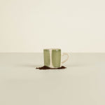 Green ceramic mug with white interior on a beige background