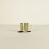Green ceramic mug with white interior on a beige background