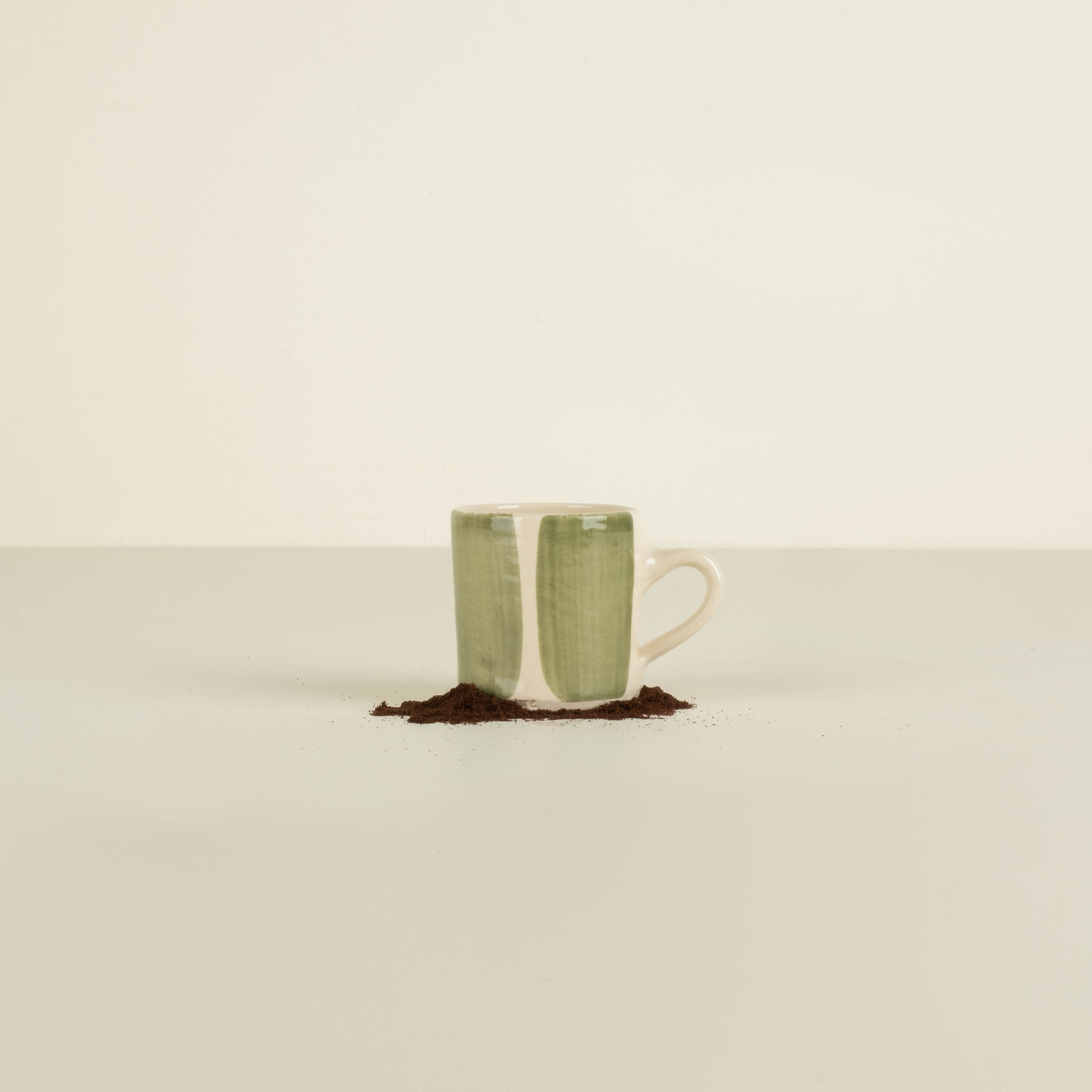 Green ceramic mug with white interior on a beige background