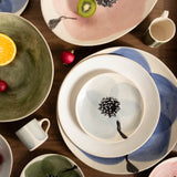 Assorted ceramic plates and bowls with floral designs on a wooden table.