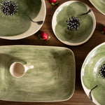 Green ceramic dishes with floral designs on a wooden surface.