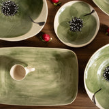 Green ceramic dishes with floral designs on a wooden surface.