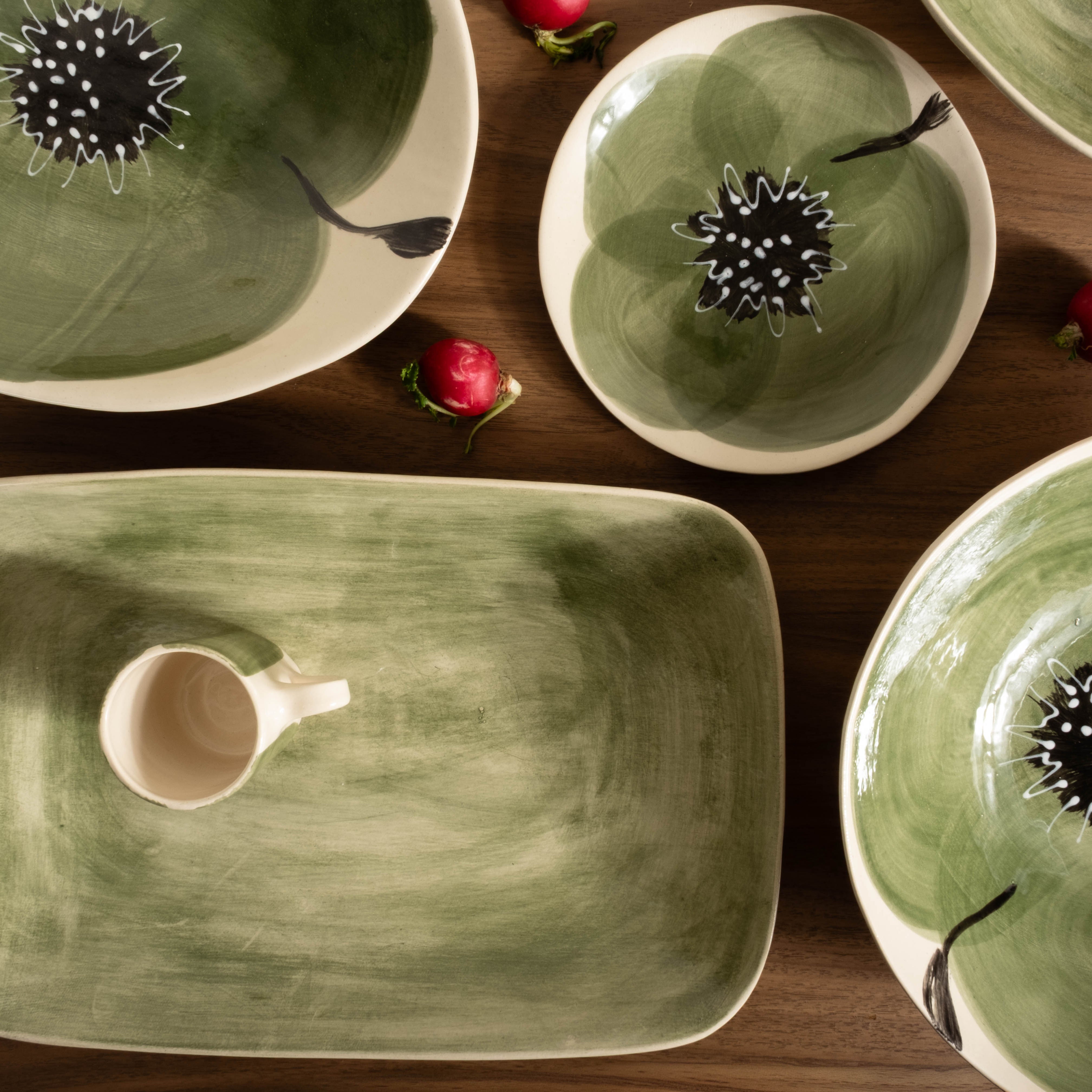 Green ceramic dishes with floral designs on a wooden surface.