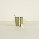 Green ceramic mug with a spoon on a beige background