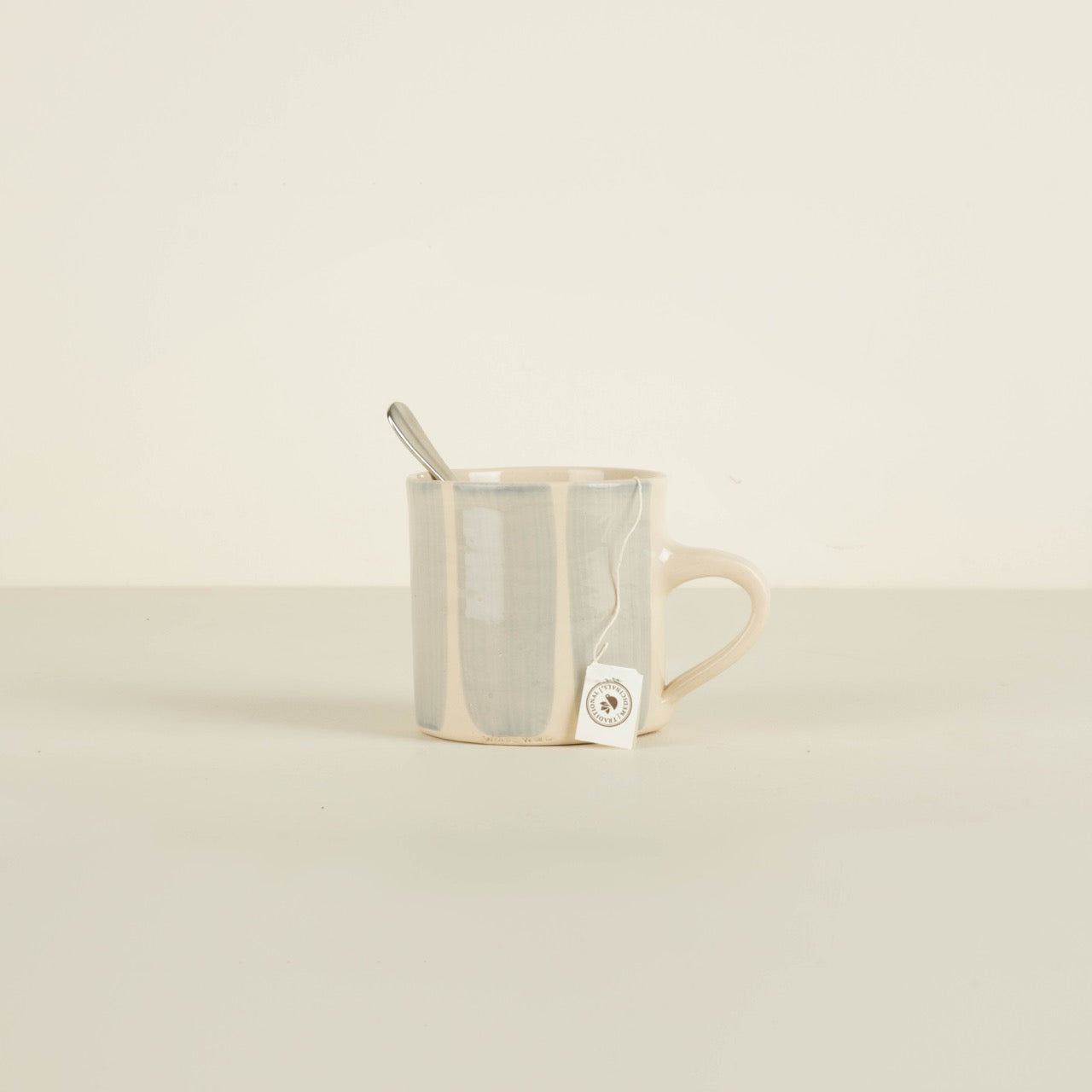 Clear mug with a metal spoon on a beige background