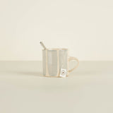 Clear mug with a metal spoon on a beige background