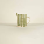 Green and white ceramic pitcher on a beige background