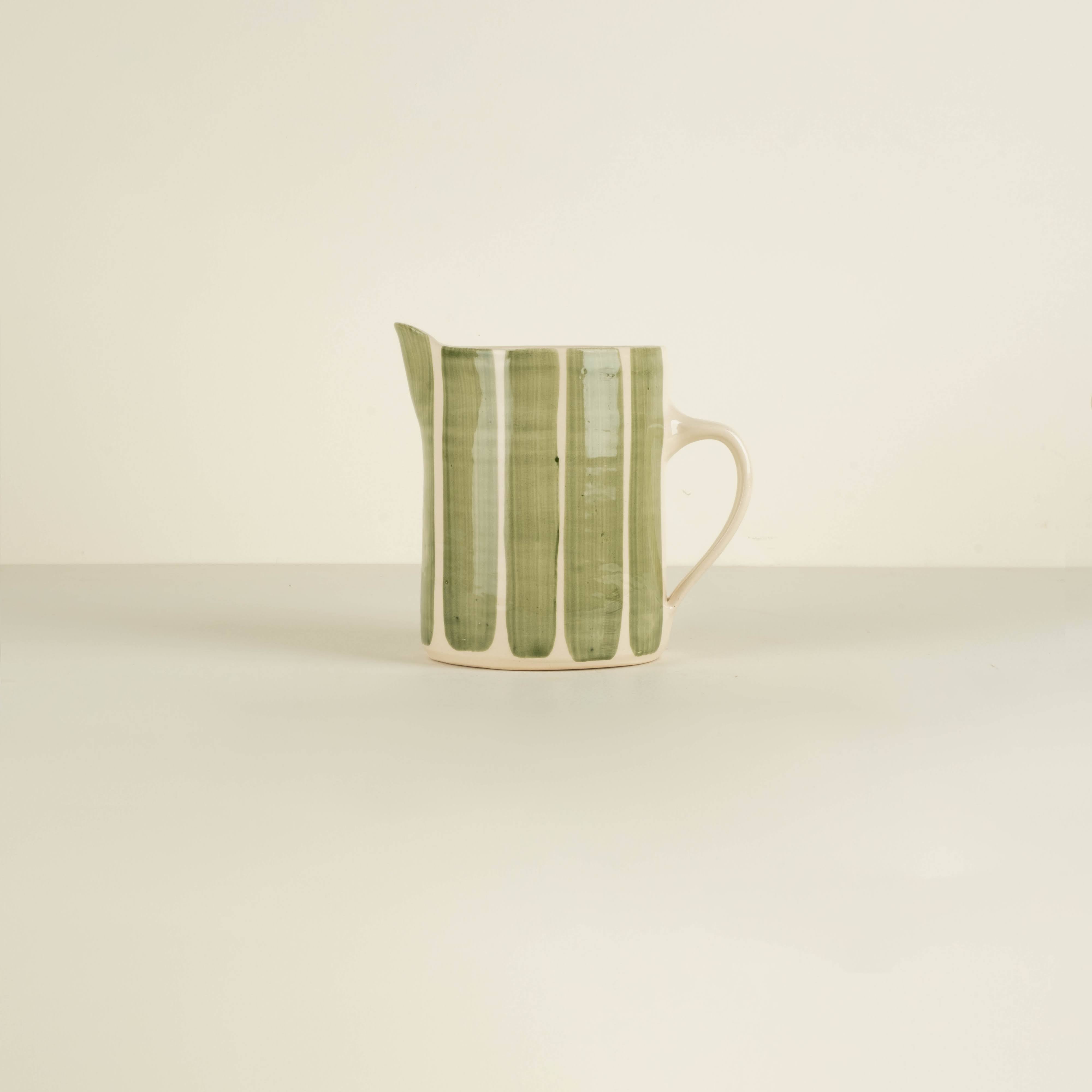 Green and white ceramic pitcher on a beige background