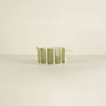 Ceramic cup with green stripes on a beige background