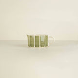 Ceramic cup with green stripes on a beige background