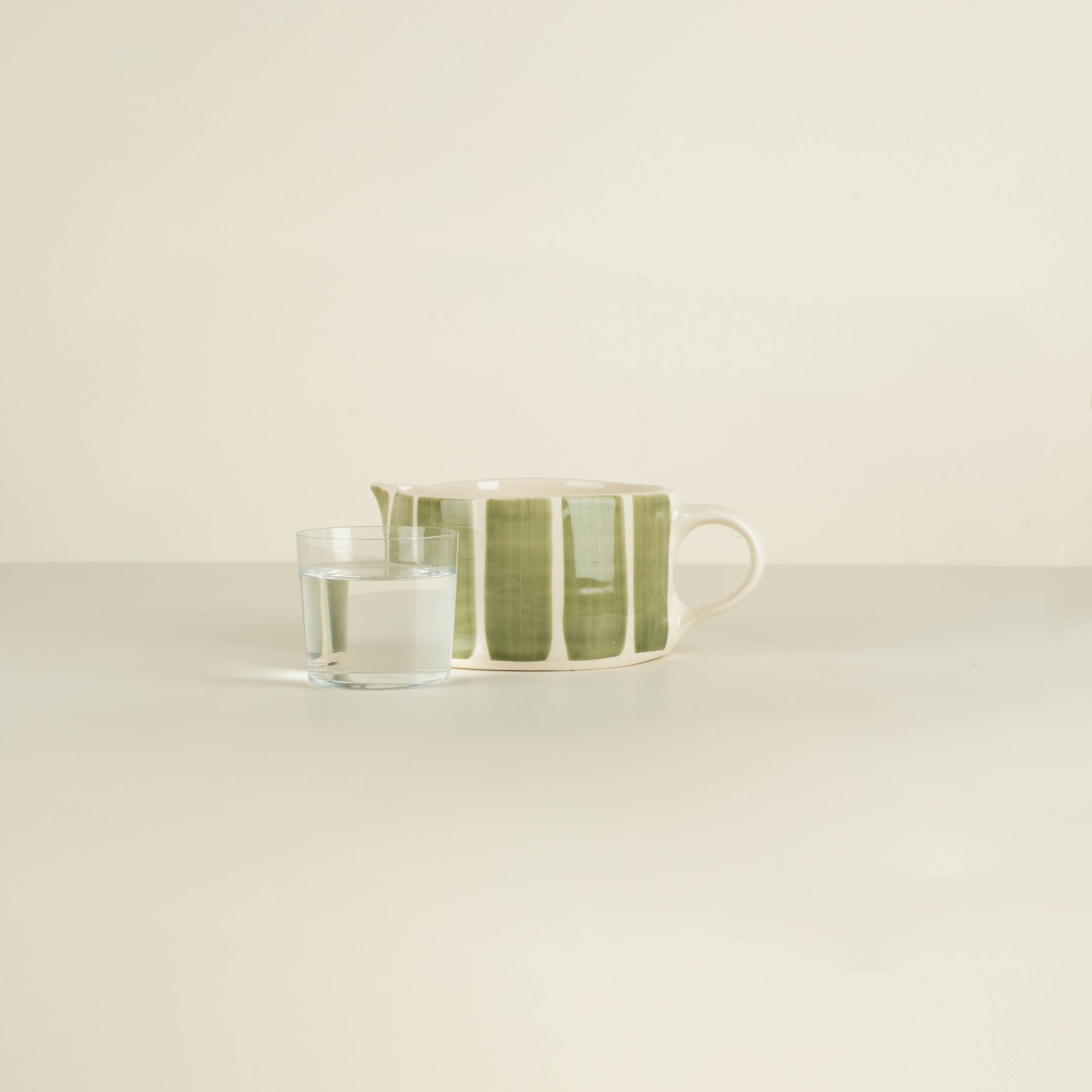 Ceramic cup with green stripes on a white surface