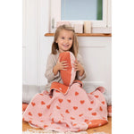 Child holding a heart-patterned blanket in a home setting