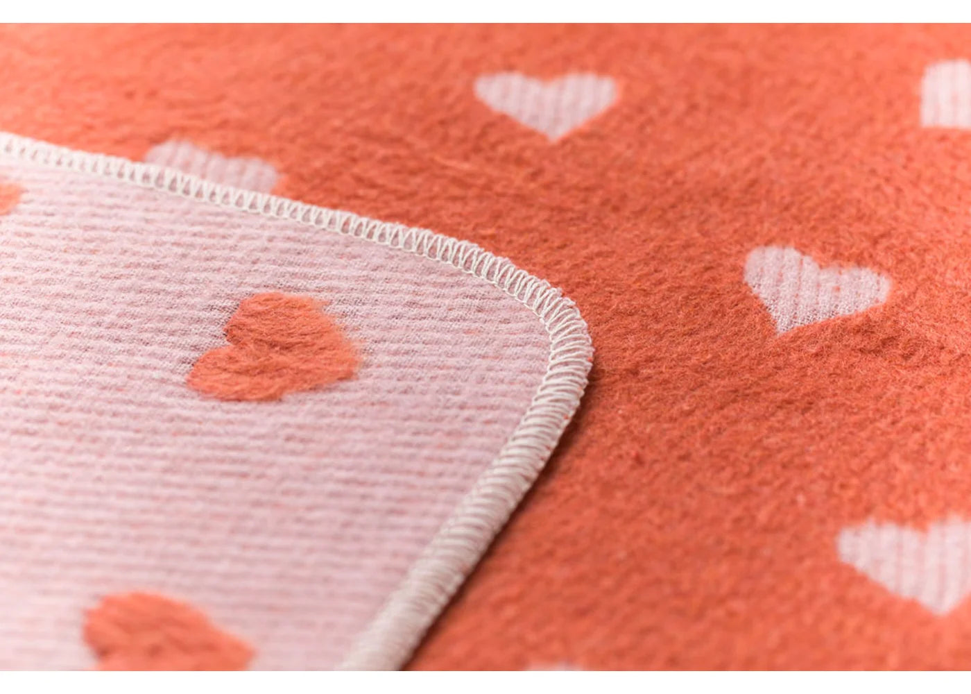 Close-up of a textured fabric with heart patterns on an orange background