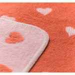 Close-up of a textured fabric with heart patterns on an orange background