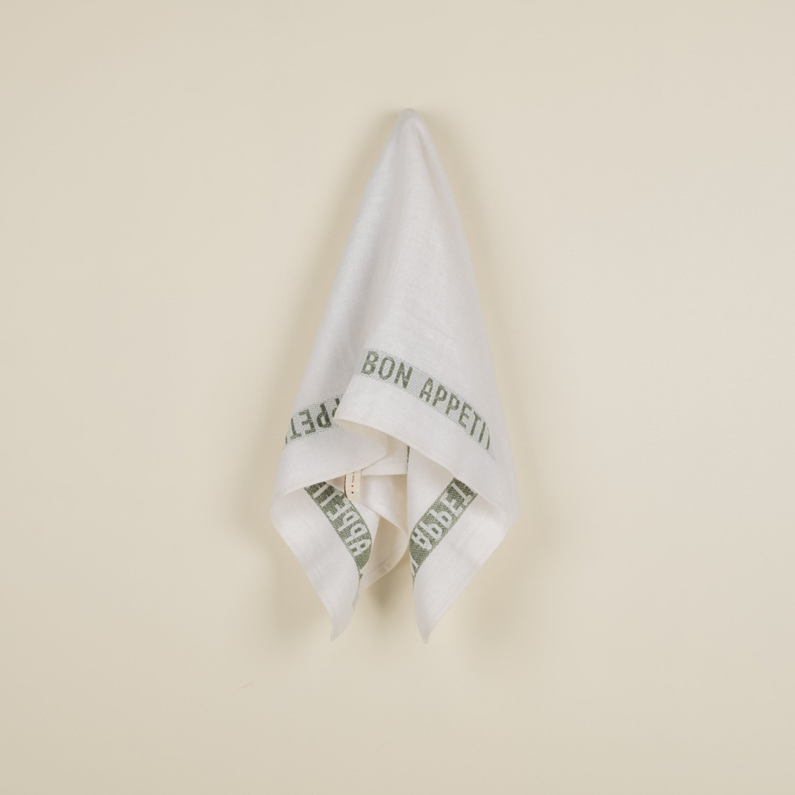 A white linen tea towel with the text 'BON APPETIT' printed in green.