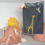 Children's blankets with giraffe designs hanging on a line against a light gray wall.