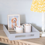 Chiffon tray with two mugs and a framed picture of a dog on a wooden surface.