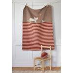 Striped towel with cat design hanging on a line against a white wall.