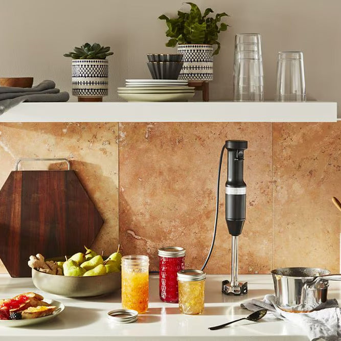 Kitchen counter with a blender, glasses, and food items on a tiled backsplash.