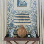 Decorative table with lamp, denim silver picture frames, and clock against floral wallpaper