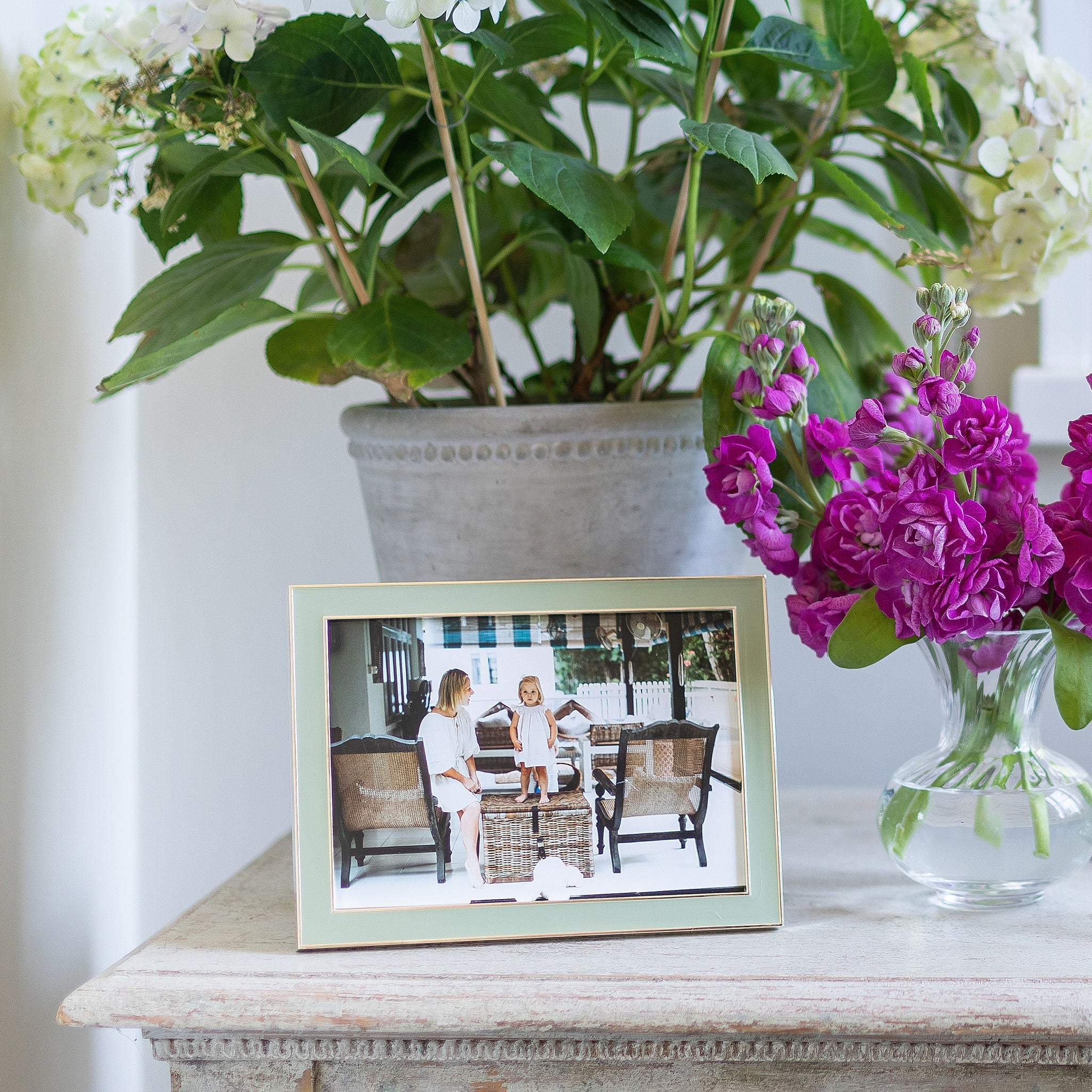 Sage silver framed photo of a couple on a table with flowers and a plant in the background